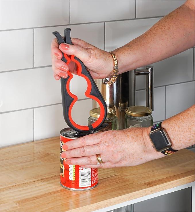 Hand using jar opener tool to open a can on a kitchen countertop with glass jars nearby