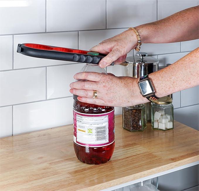 Hands using an easy-grip jar opener tool to open a bottle on a kitchen countertop