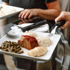 Adaptive utensils with large grips used to eat mashed potatoes, green beans, and meatloaf