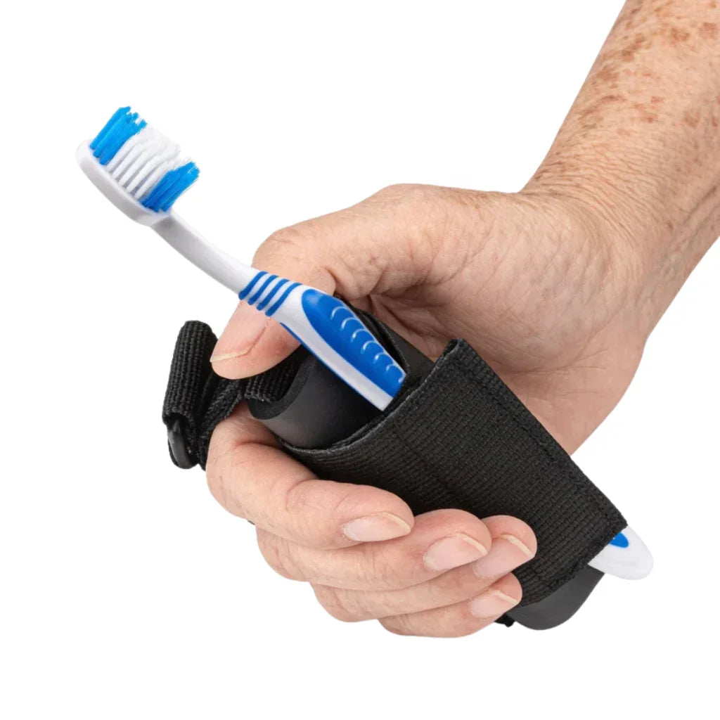 Hand holding adaptive grip aid with a toothbrush secured for easy use