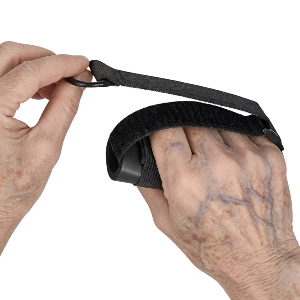 Elderly hand using black adaptive grip aid with adjustable strap for limited mobility