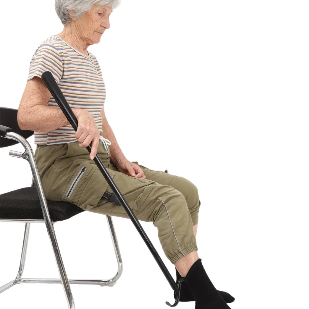 Senior woman using adaptive sock aid tool while seated in a chair