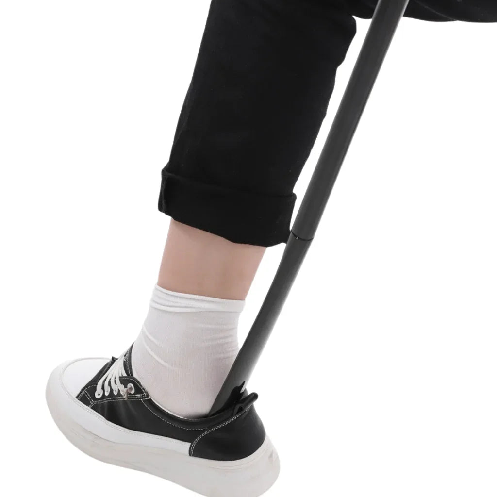 Adaptive shoehorn helping person put on black sneaker with white sole