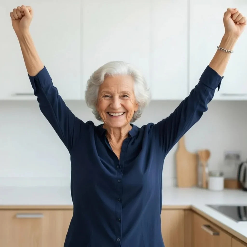Happy elderly woman with raised arms smiling in a modern kitchen, celebrating independence and mobility.