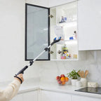 Person using a long reach grabber tool to retrieve an item from a high kitchen cabinet