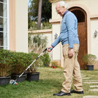 Senior man using a long reach grabber tool to pick up litter in a garden yard