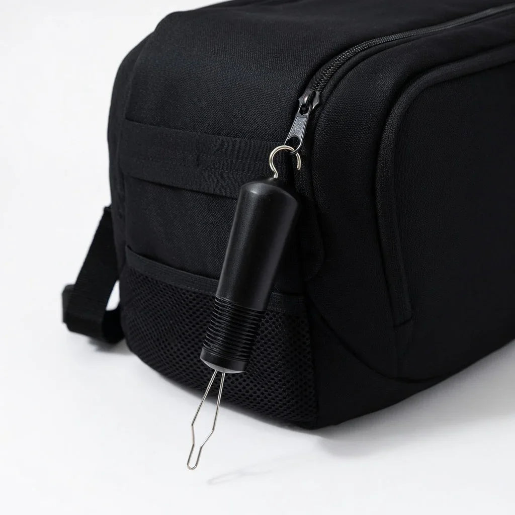 Adaptive button hook zipper pull attached to black bag, arthritis-friendly tool for easy use