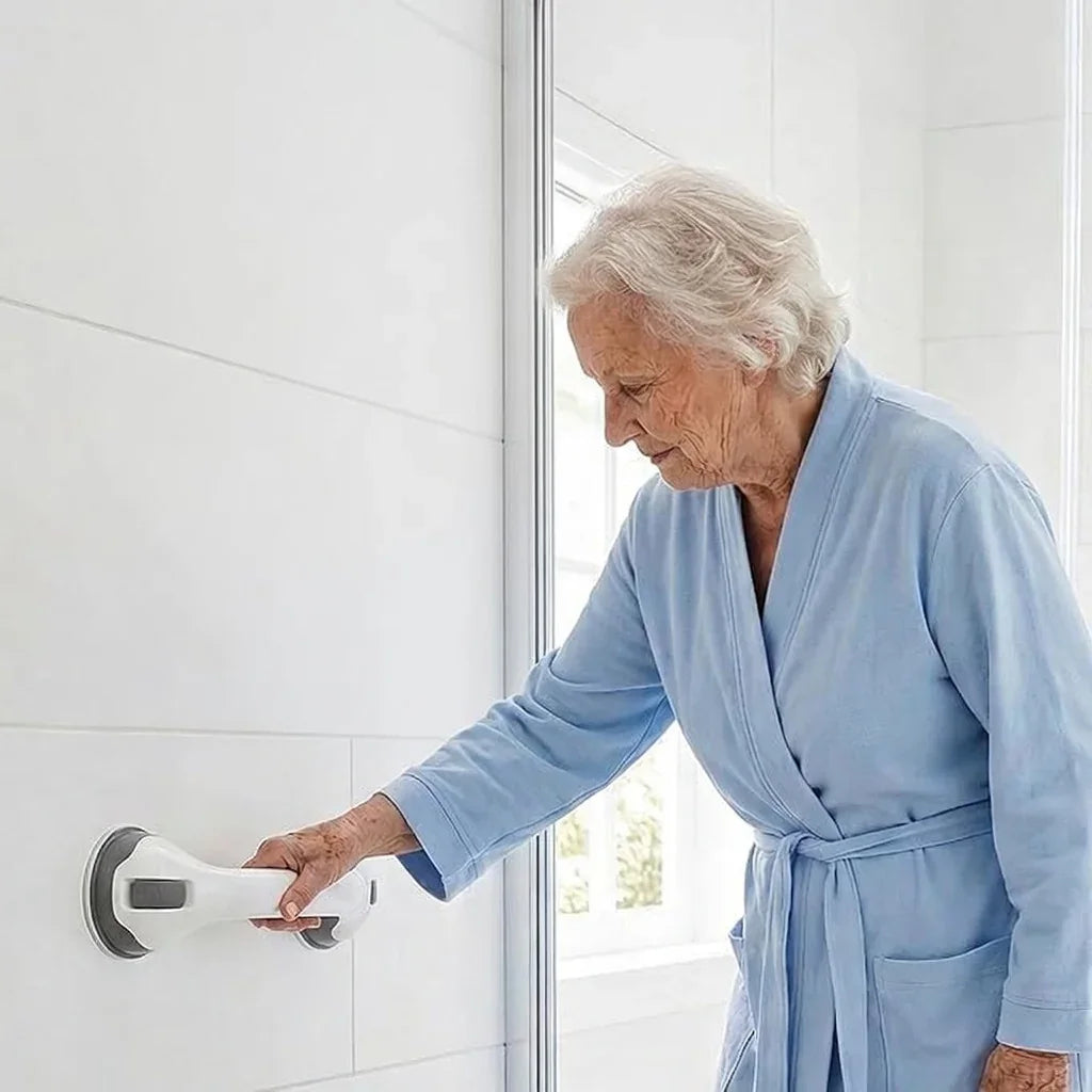 Elderly woman using a suction grab bar for support in a tiled bathroom.