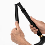 Hands folding a black adjustable walking cane for mobility support