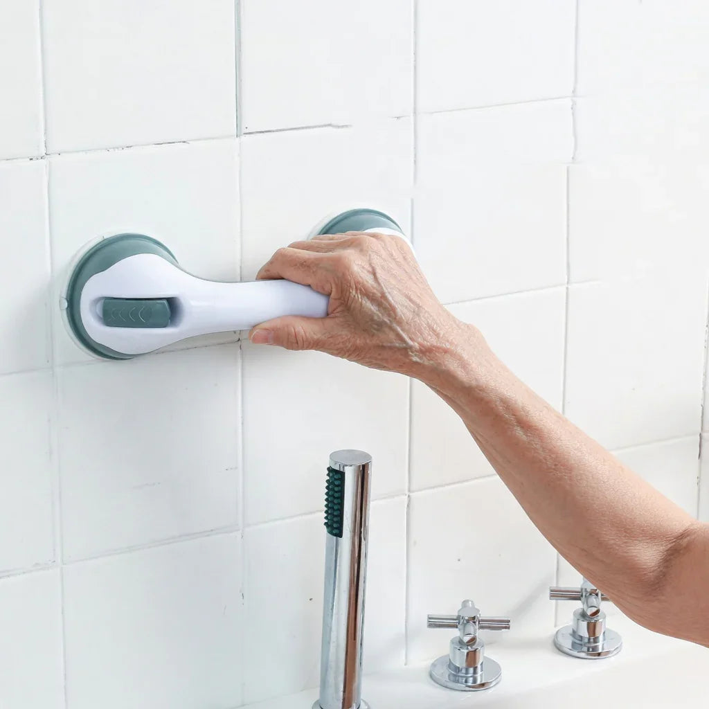 Elderly hand gripping a bathroom suction grab bar for safety and support on tiled wall