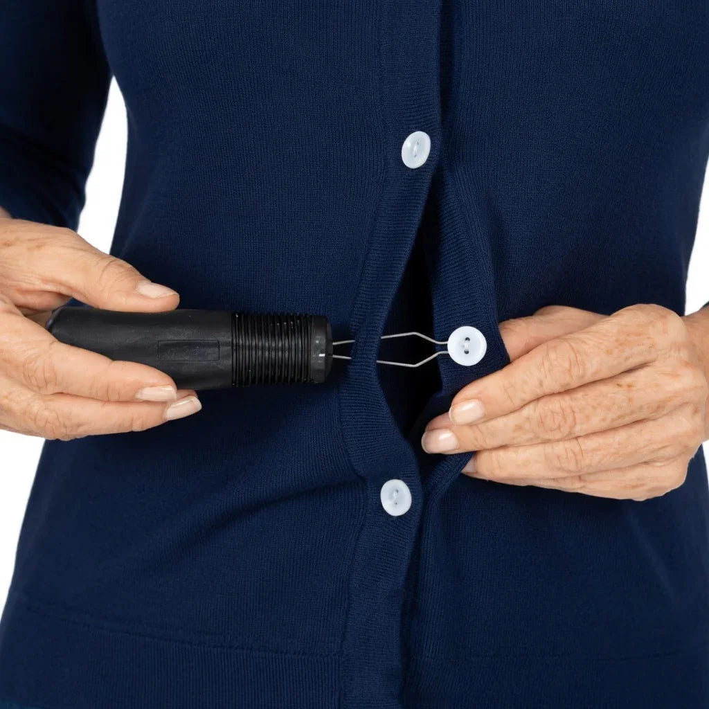 Hands using a button hook aid to fasten a button on a blue cardigan