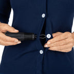 Hands using a button hook aid to fasten a button on a blue cardigan