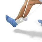 Person using sock aid device to easily put on blue socks, leg mobility assistance tool