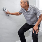 Elderly man using a suction grab bar for bathroom safety near a toilet