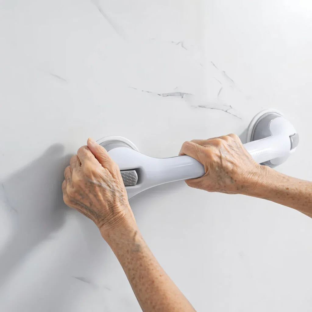 Elderly hands gripping a suction grab bar on a smooth bathroom wall for support and stability